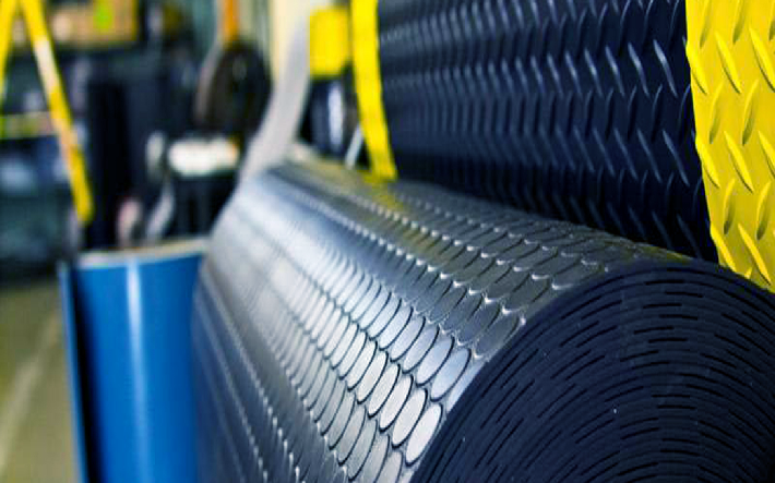 Rubber unit showing conveyor belts, machinery, and workers, processing rubber materials for various applications.